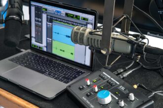Professional podcast equipment setup featuring a microphone, headphones, audio interface, camera, and lighting for high-quality audio and video recording.